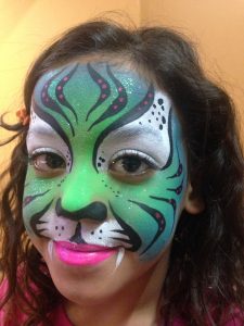 A smiling girl with a tiger face painting by Facepainterina.